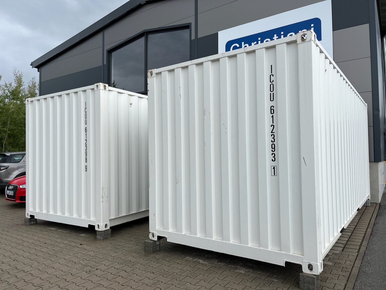 Zwei weiße 20-Fuß-Container nebeneinander auf dem Betriebsgelände