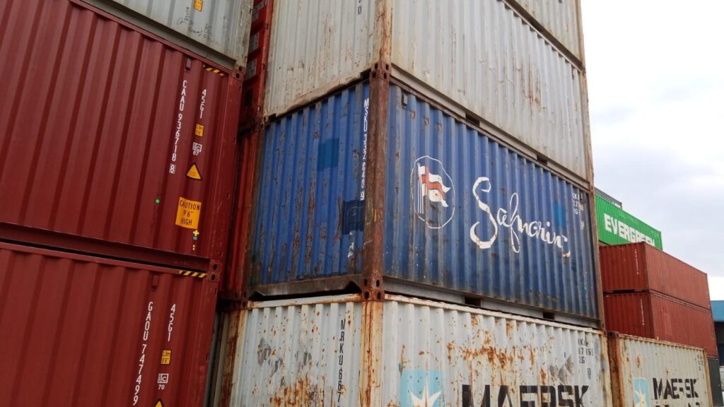 Gestapelte gebrauchte Seecontainer im Depot, in der Mitte ein blauer 20-Fuß-Container
