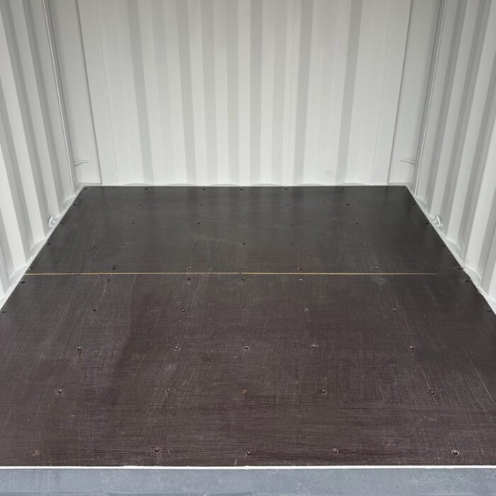 Innenraum eines 8-Fuß-Containers mit Sperrholzboden und weißen Wänden