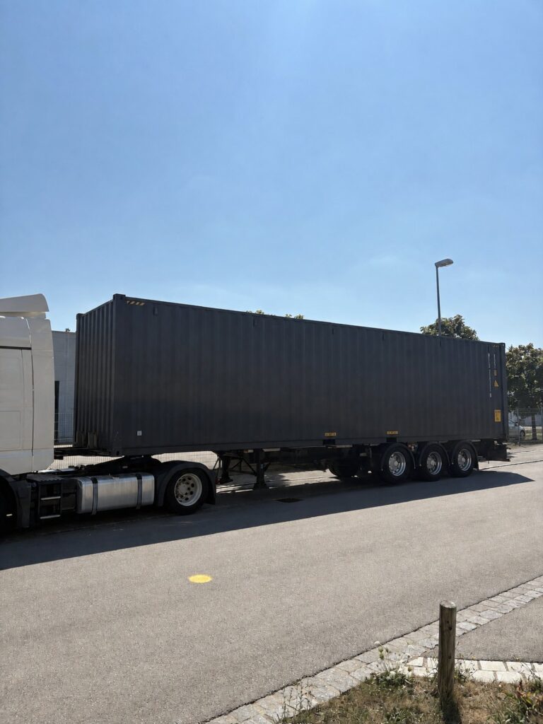 Dunkler 40-Fuß-Container auf einem dreiachsigen Sattelauflieger